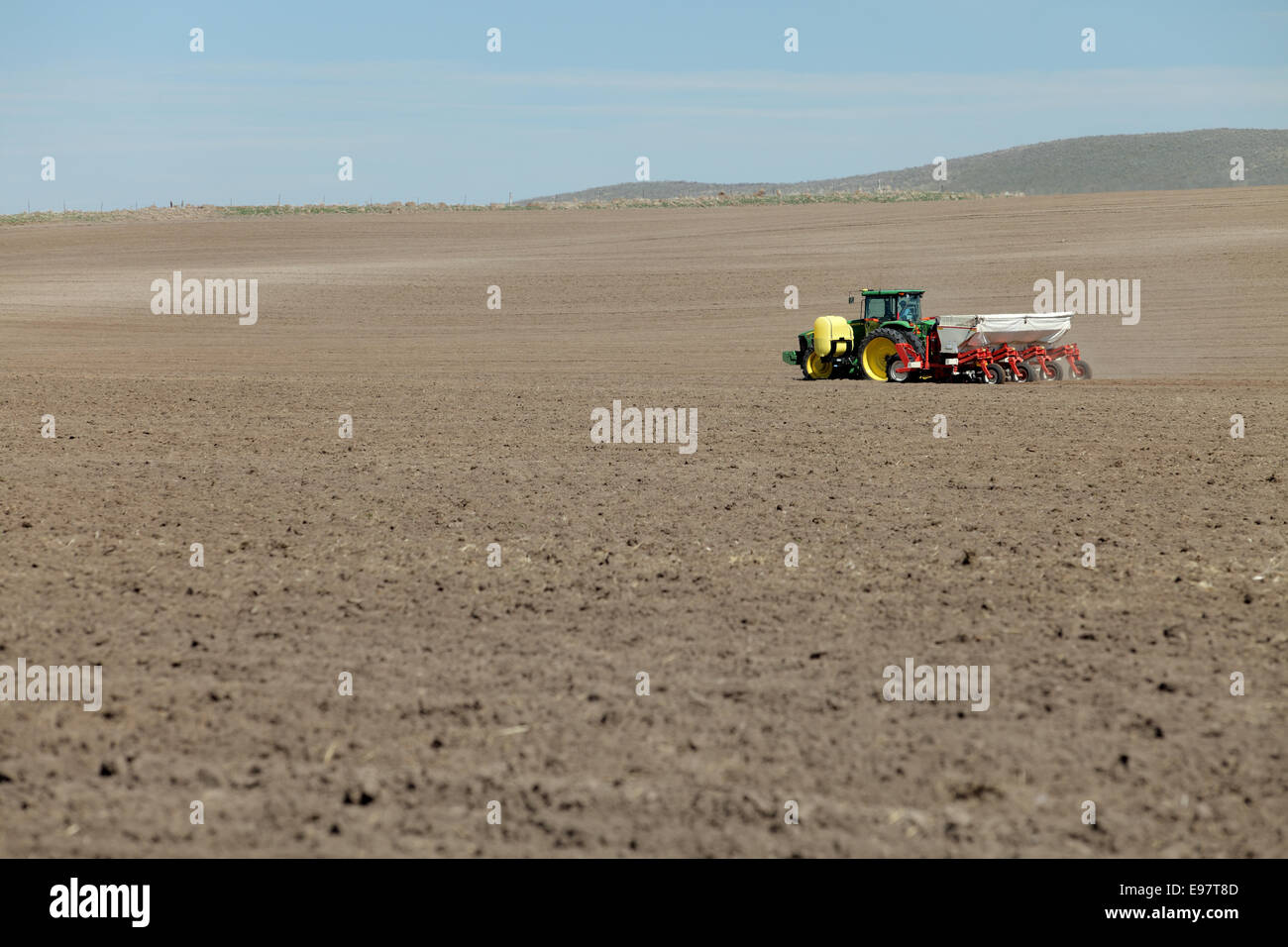 Tractors working planting potatoes in the fertile farm fields of Idaho. Stock Photo