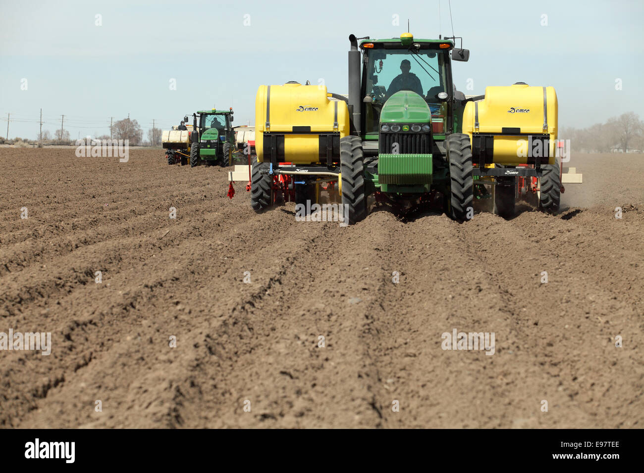 Tractors working planting potatoes in the fertile farm fields of Idaho. Stock Photo