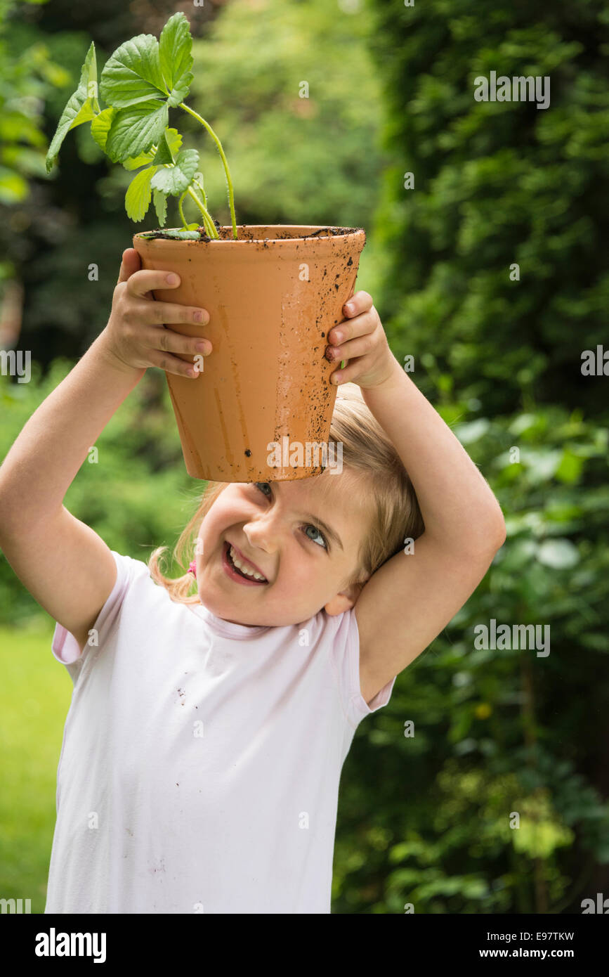 Little girl gardening, holding potted plant in hands Stock Photo - Alamy