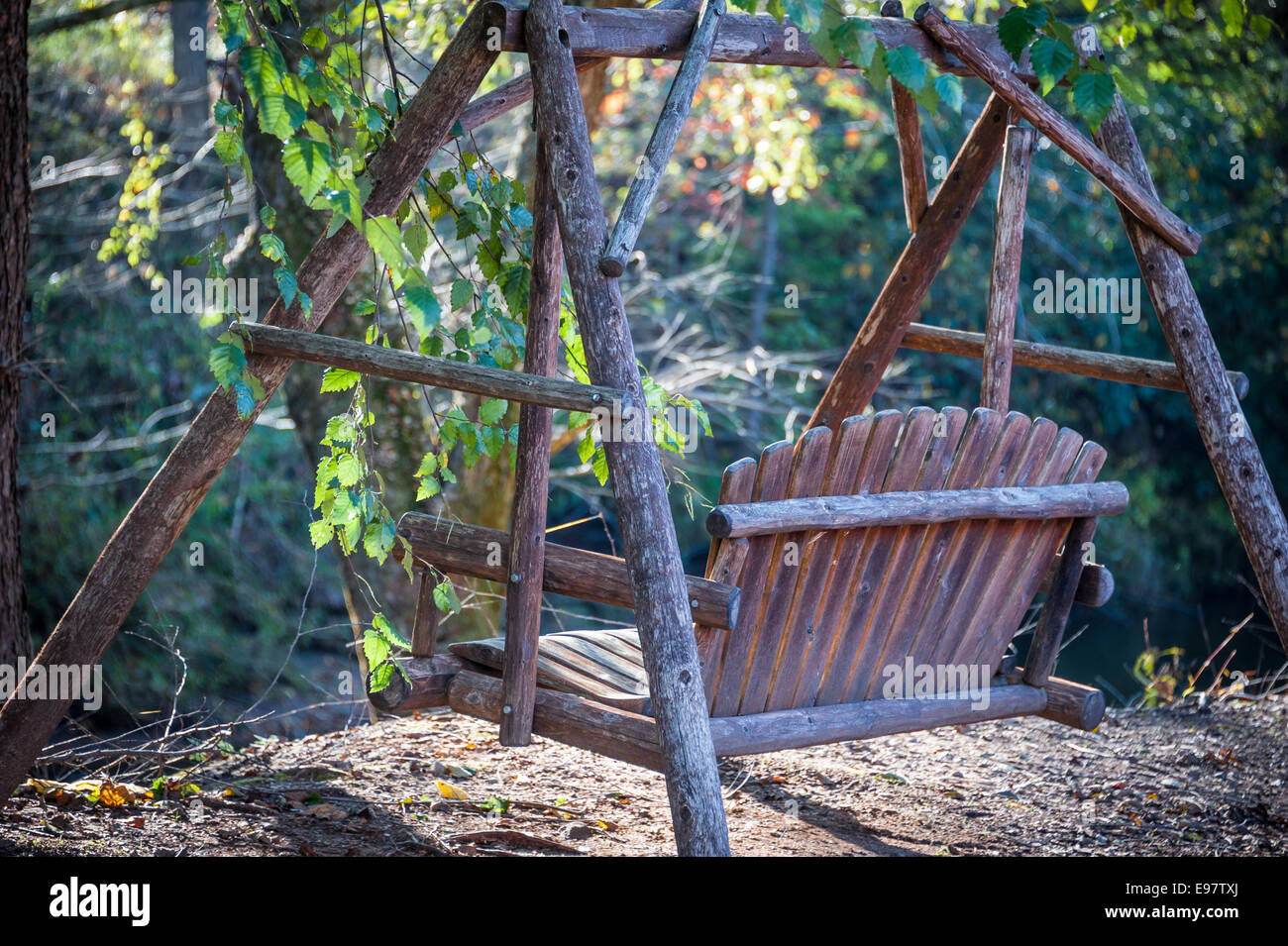 Late afternoon view of a wooden bench swing along the creekside at