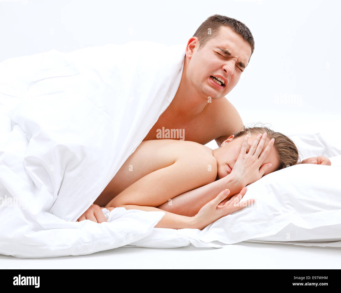 Young, naked couple in bed, the man leaning over the woman Stock Photo