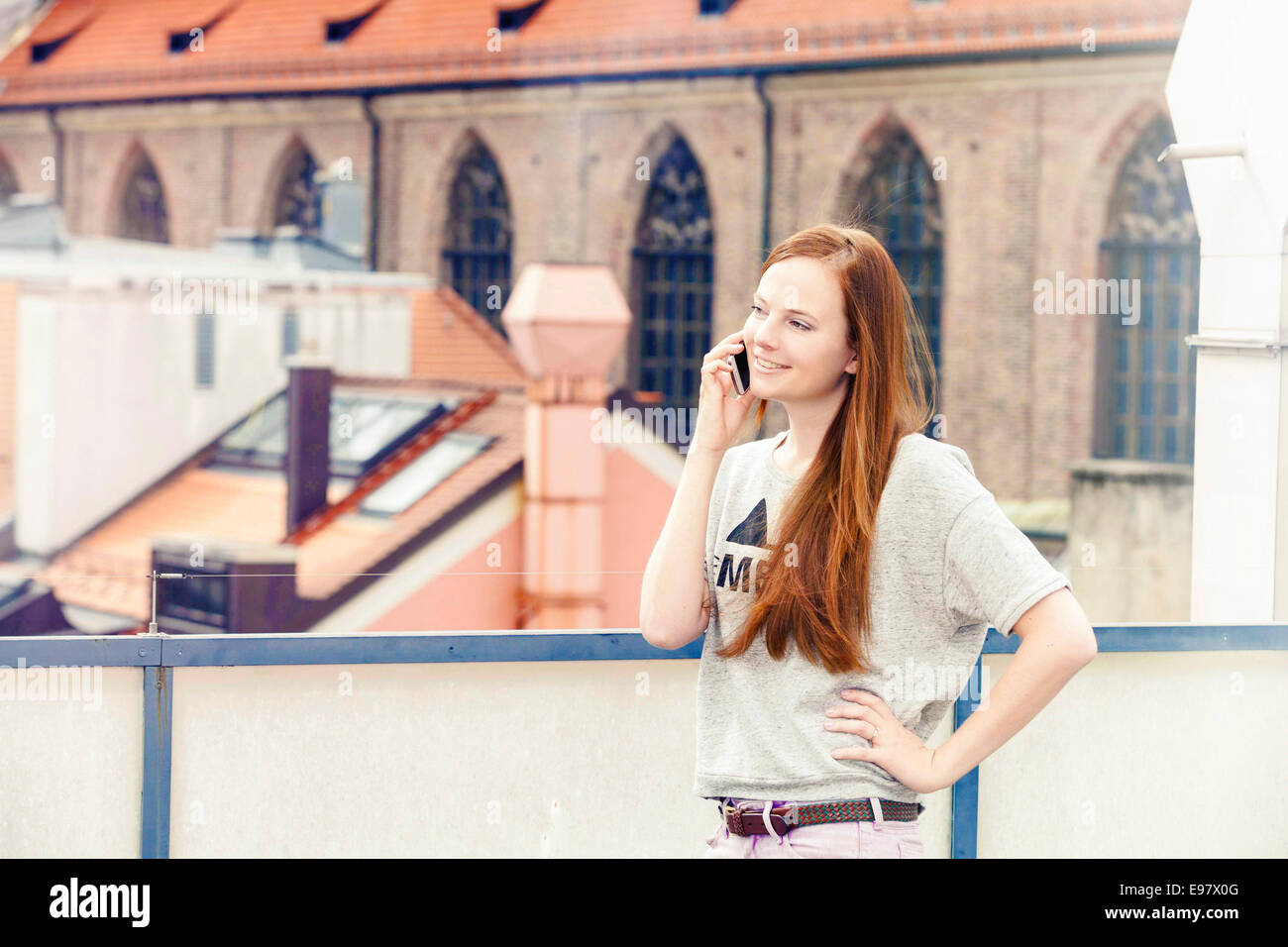Young woman using smart phone on balcony, Munich, Bavaria, Germany Stock Photo