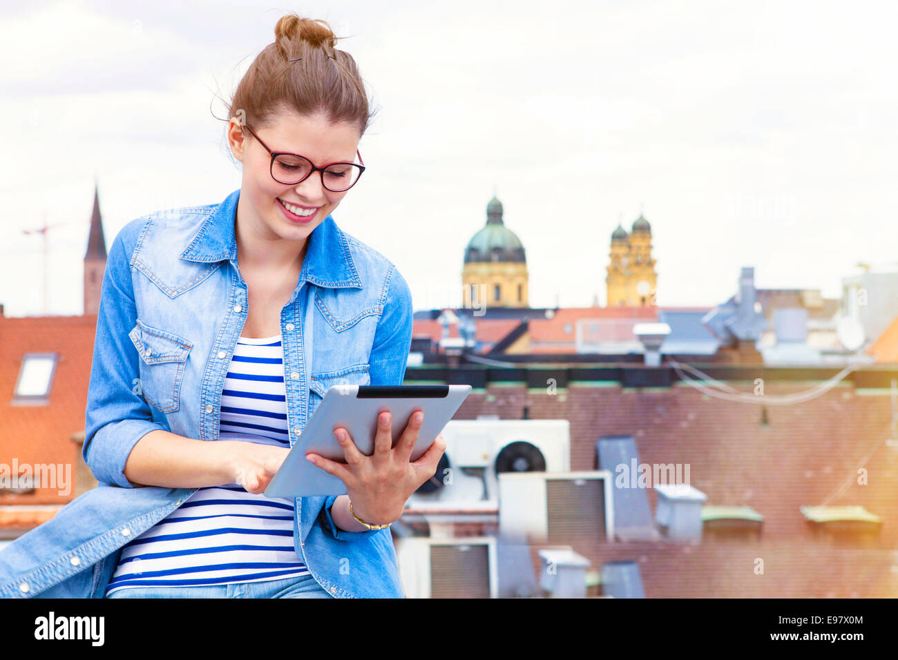 Young woman using digital tablet on balcony, Munich, Bavaria, Germany Stock Photo