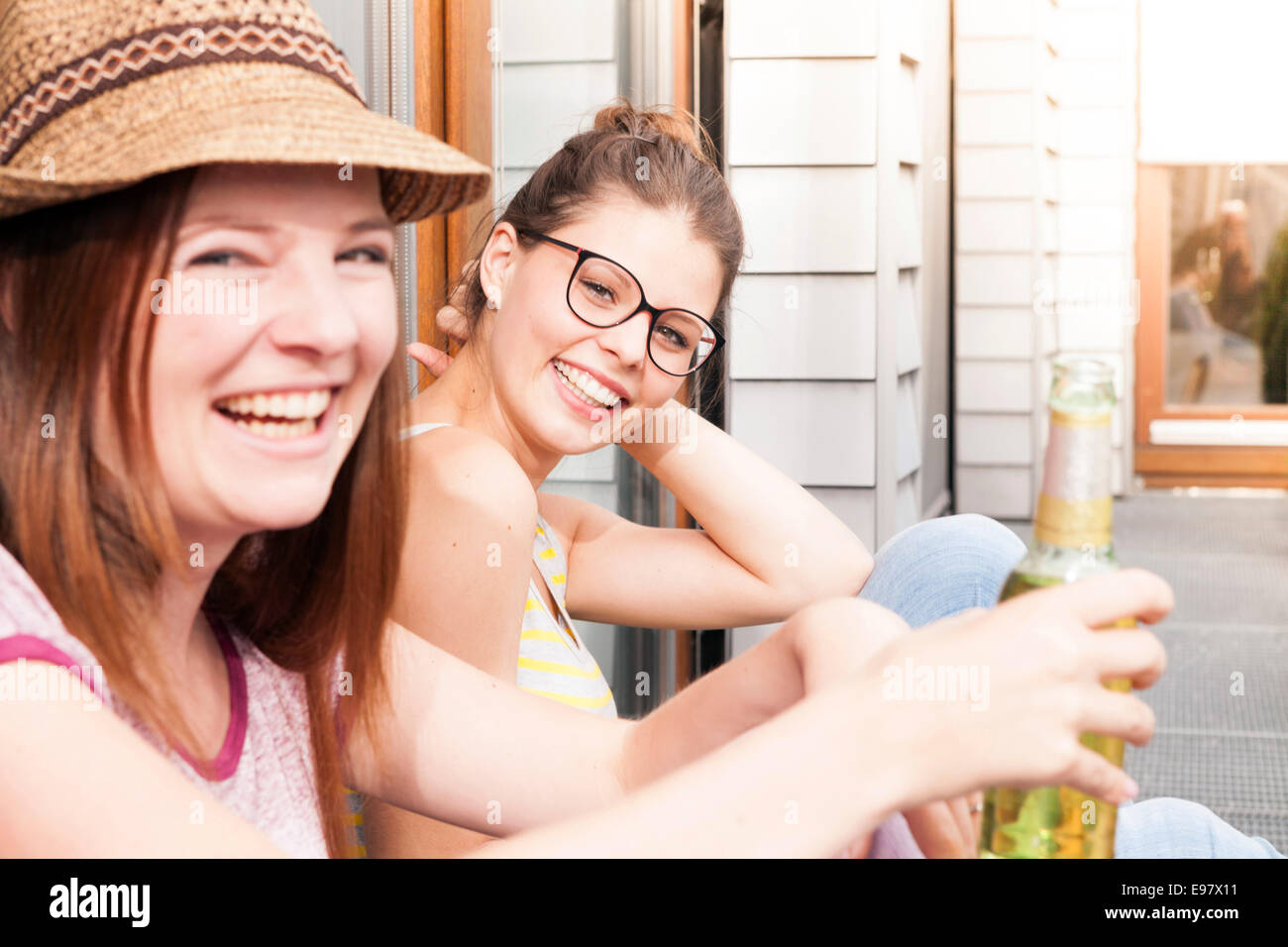 Two young women drinking beer on balcony, Munich, Bavaria, Germany Stock Photo