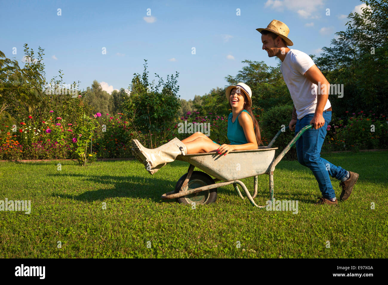 Young couple with wheelbarrow fooling about Stock Photo