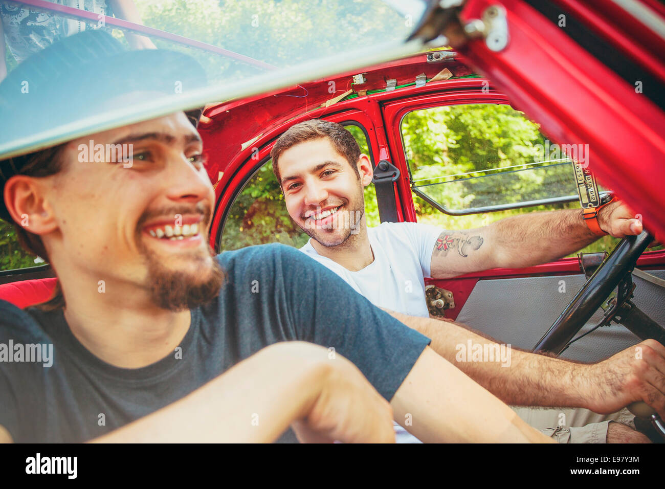 Portrait of two young men in red car smiling merrily Stock Photo - Alamy