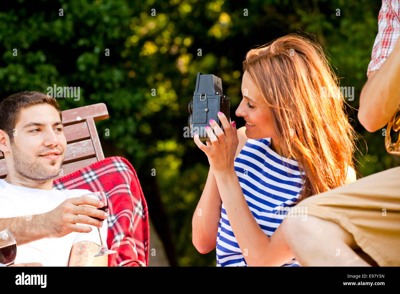 Young woman taking a picture of boyfriend outdoors Stock Photo