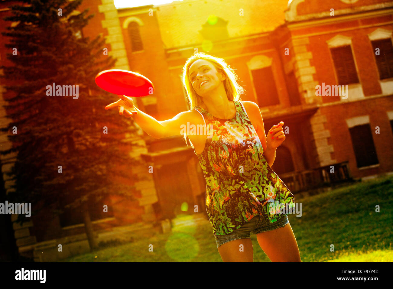 Young woman playing frisbee outdoors with back light Stock Photo