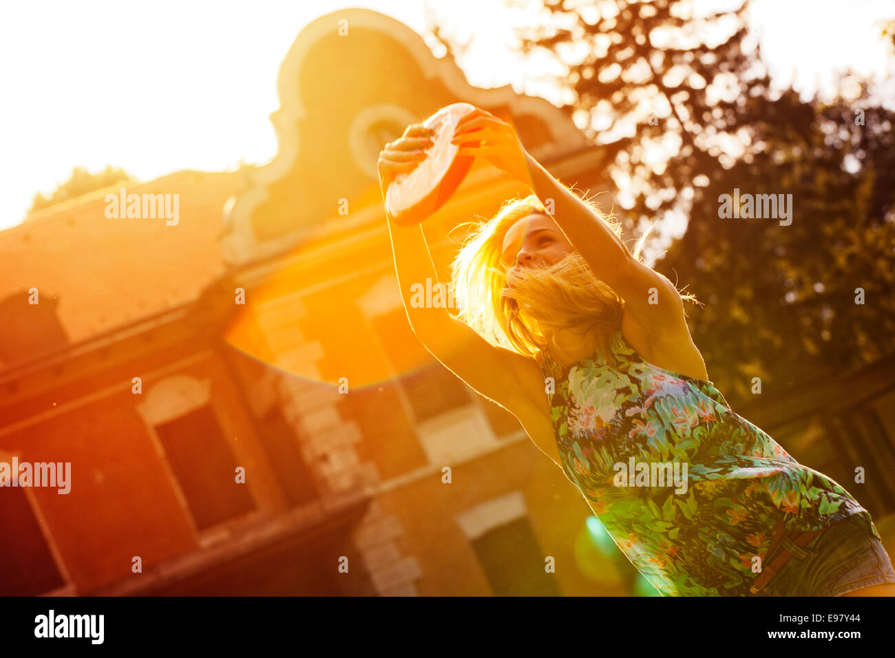 Young woman playing frisbee outdoors with back light Stock Photo