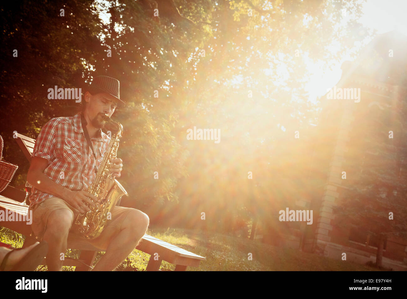 Young man playing saxophone outdoors with back light Stock Photo