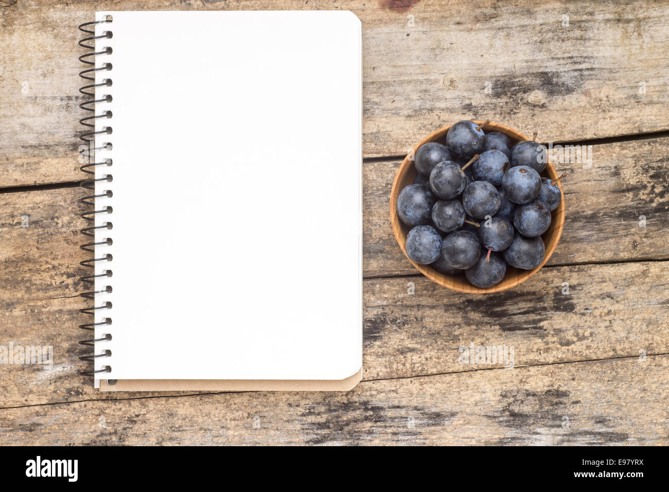 Fresh blueberry or blackthorn berries with blank recipe book on wood background Stock Photo