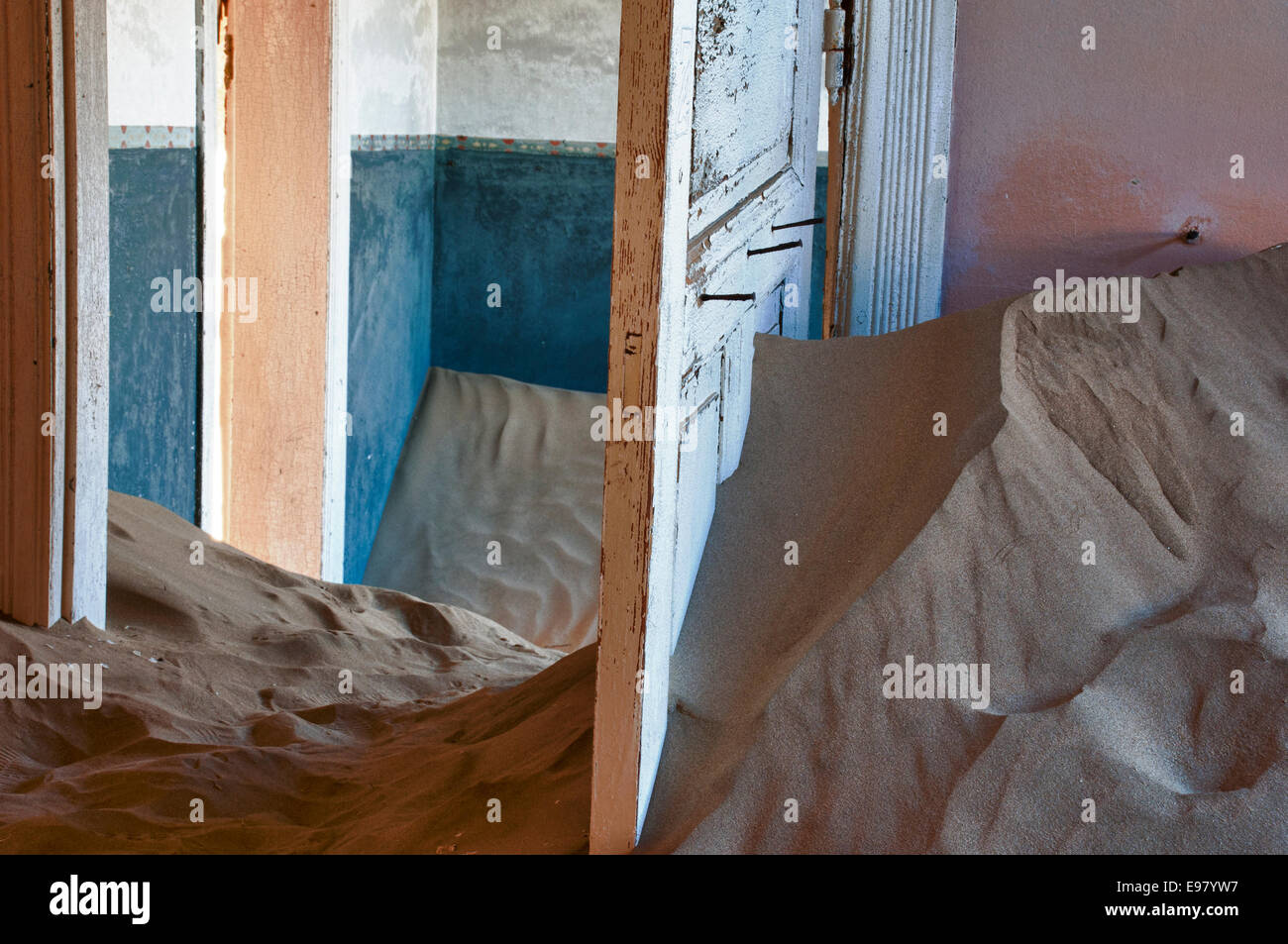 Open doors in a room full of sand in Kolmanskop, a ghost mining town in Namibia, Africa. The desert has reclaimed the town. Stock Photo