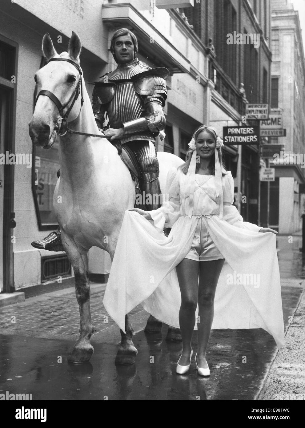 London, UK, UK. 17th June, 1971. Model JANET TILLETT is seen off to Ascot by a knight in shining armor on a white stallion. Janet is wearing a chiffon dress in Grecian style with blue satin ribbon trim to emphasize the line. Criss cross bands mark the bodice and sleeves with matching hot pants work below the split skirt. The headdress is made of floral clusters with blue satin ribbons streaming to her shoulder. The dress is from Young's Dress Hire Collection. (Rentals) © KEYSTONE Pictures/ZUMA Wire/ZUMAPRESS.com/Alamy Live News Stock Photo