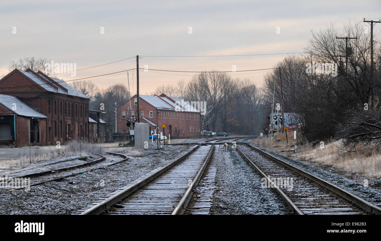 View old train station from center tracks on winters day. There is just light coating snow on tracks landscape old brick Stock Photo