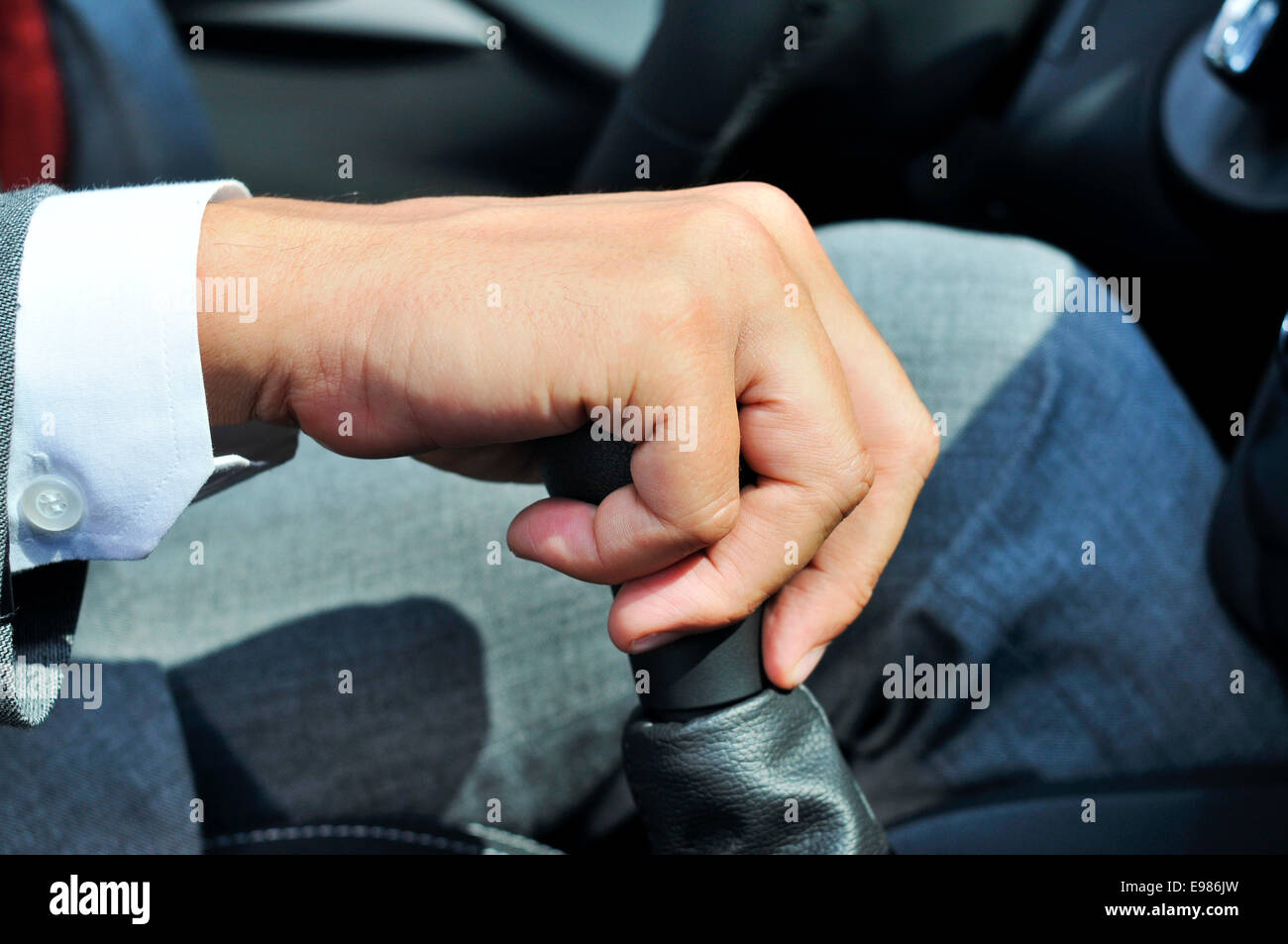 closeup of a man in suit operating the parking brake of a car Stock Photo