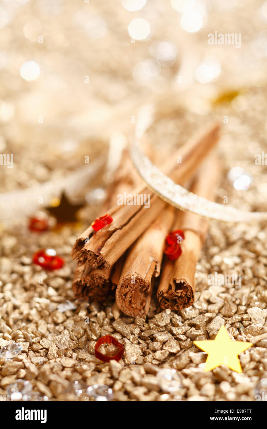 Cinnamon Sticks with a ribbon on a golden background for Christmas Concept. Stock Photo
