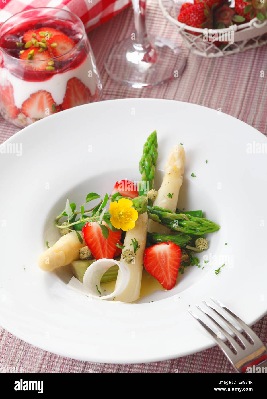Salad of freshly diced asparagus tips and strawberries served in a plain white dish. High angled view. Stock Photo