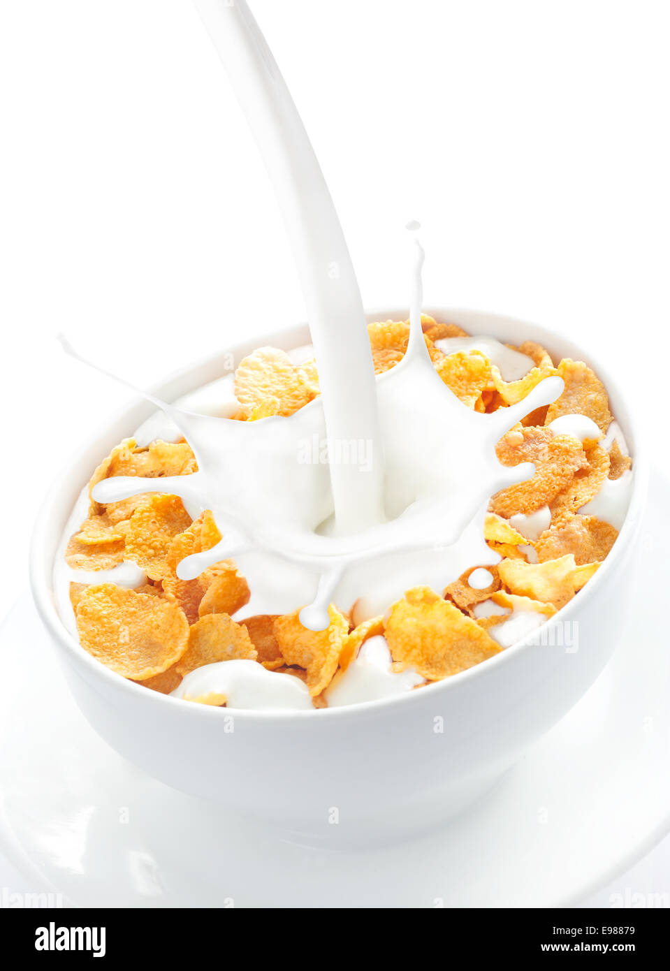 Appetizing view of milk pouring into a bowl of nutritious and delicious corn flake cereal Stock Photo