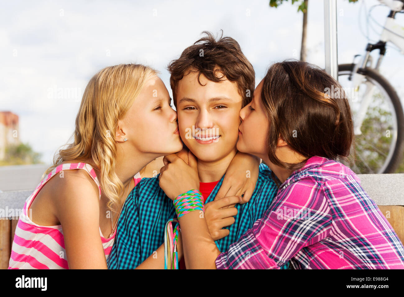 Two beautiful girls kissing smiling one cute boy Stock Photo - Alamy