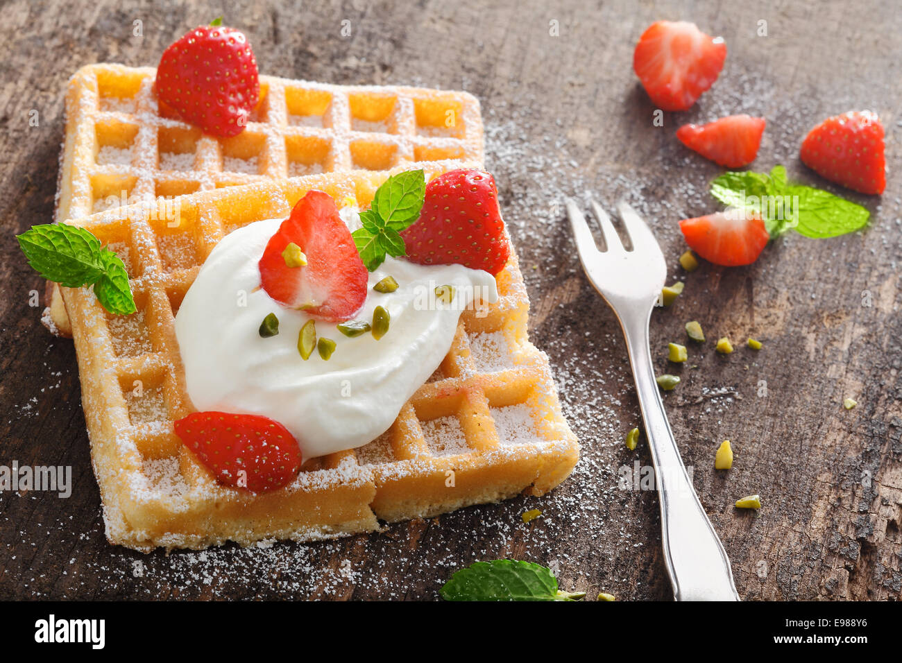 Golden waffle topped with fresh diced strawberries and a dollop of ...