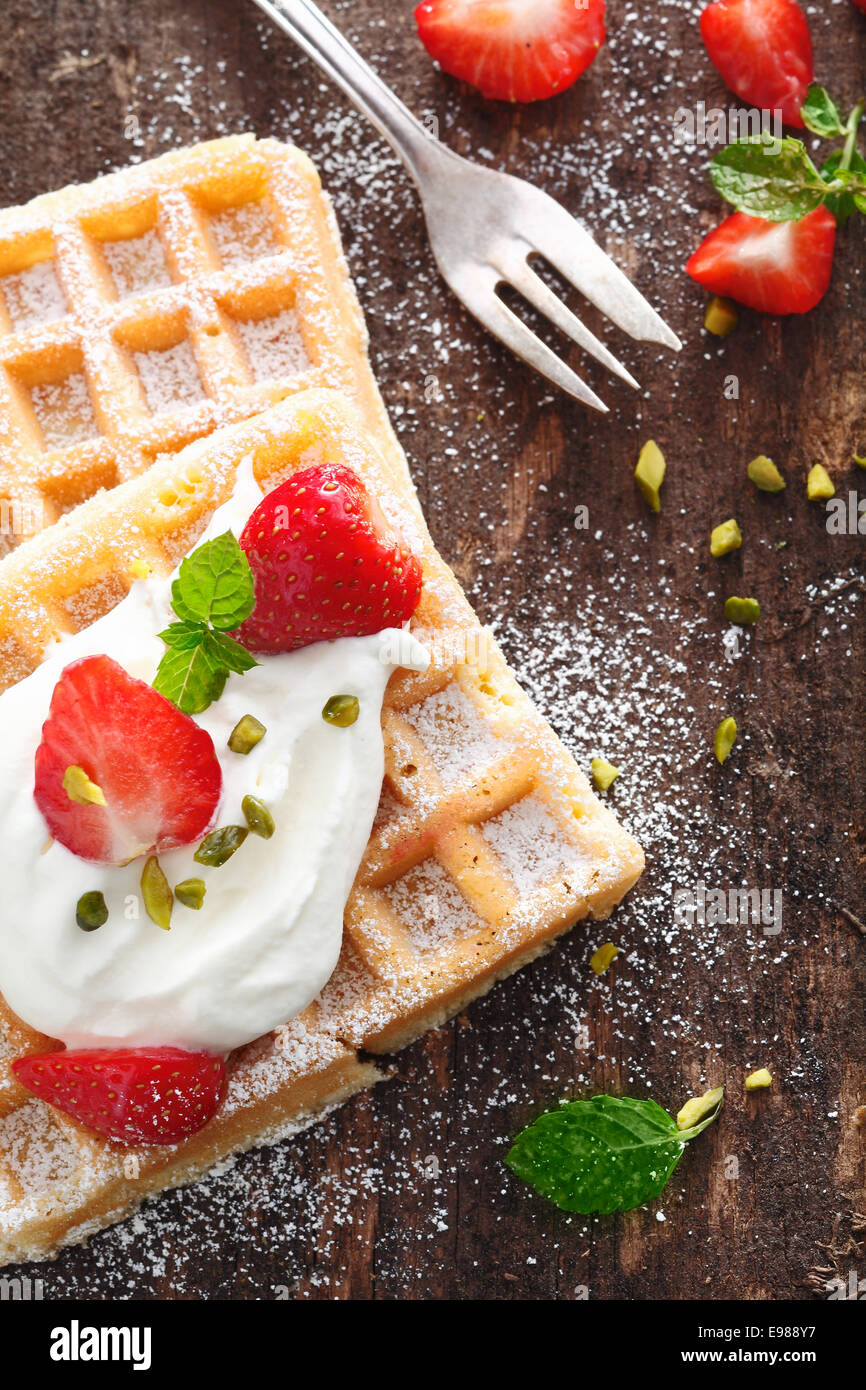 Crisp golden waffle topped with strawberries and whipped cream and ...