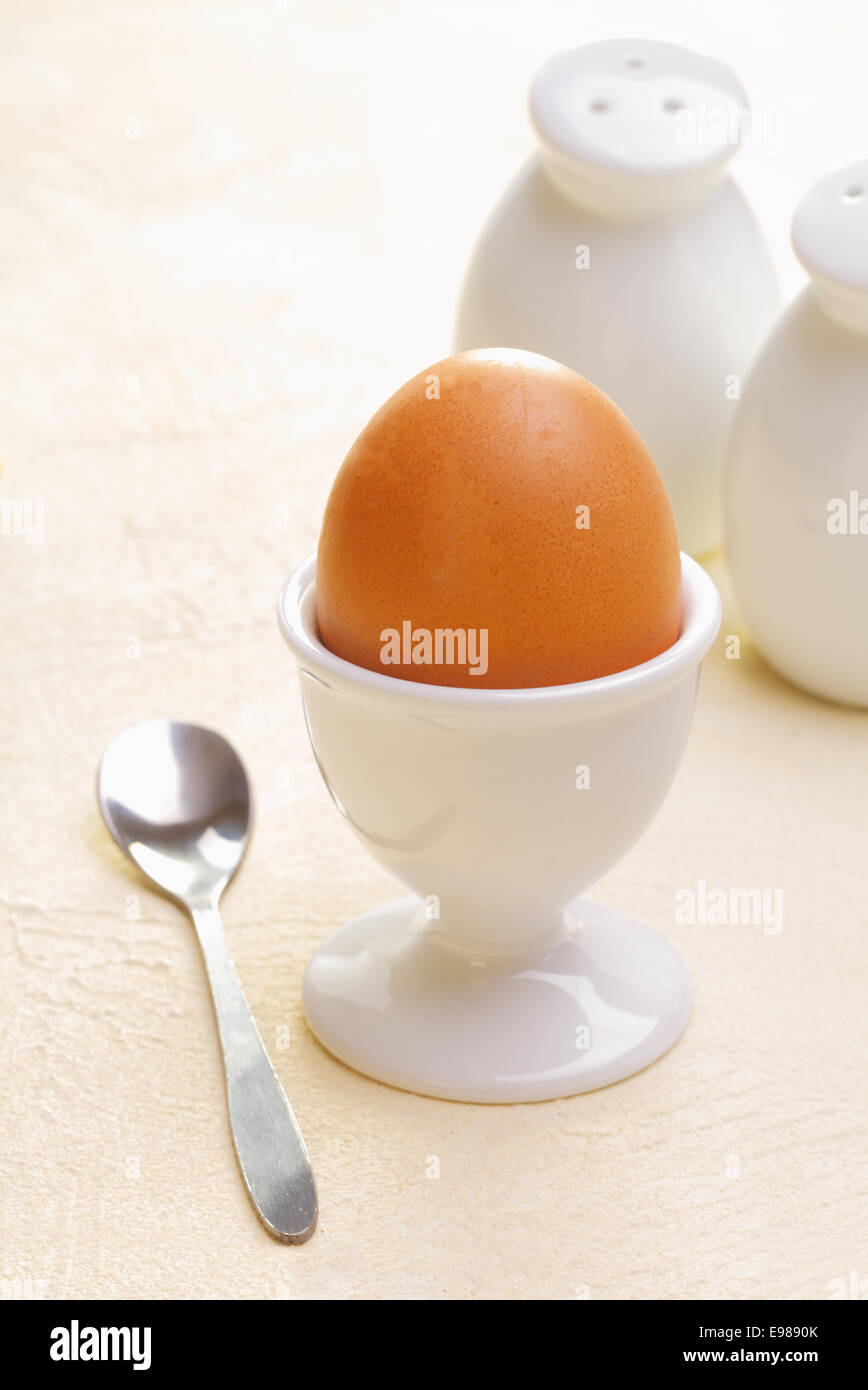 Fresh boiled egg in an eggcup with a teaspoon ready for a healthy nutritious breakfast Stock Photo