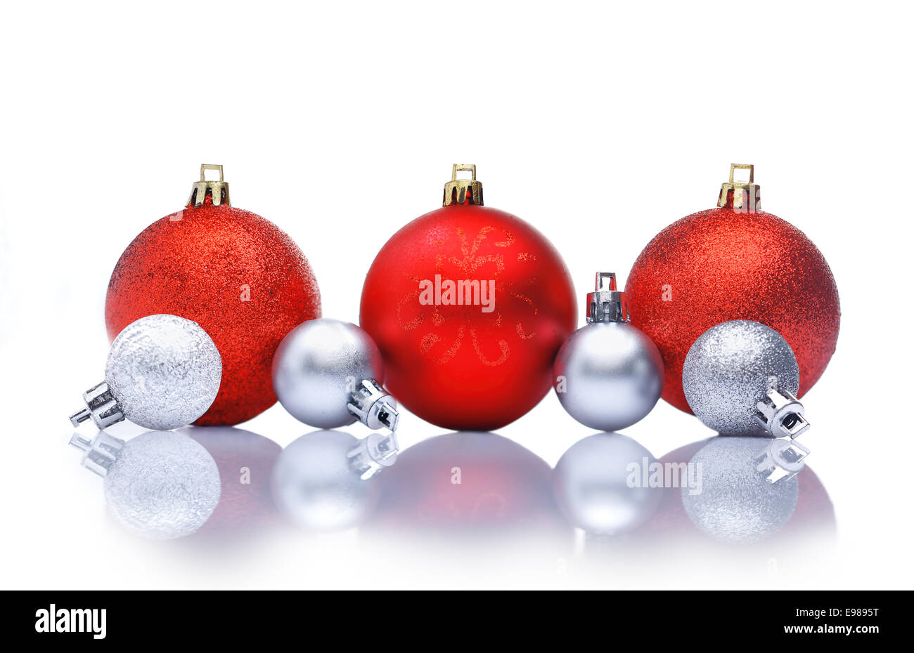 Red and silver Christmas decorations in a row with reflections and copyspace for your Christmas greetings or wishes Stock Photo