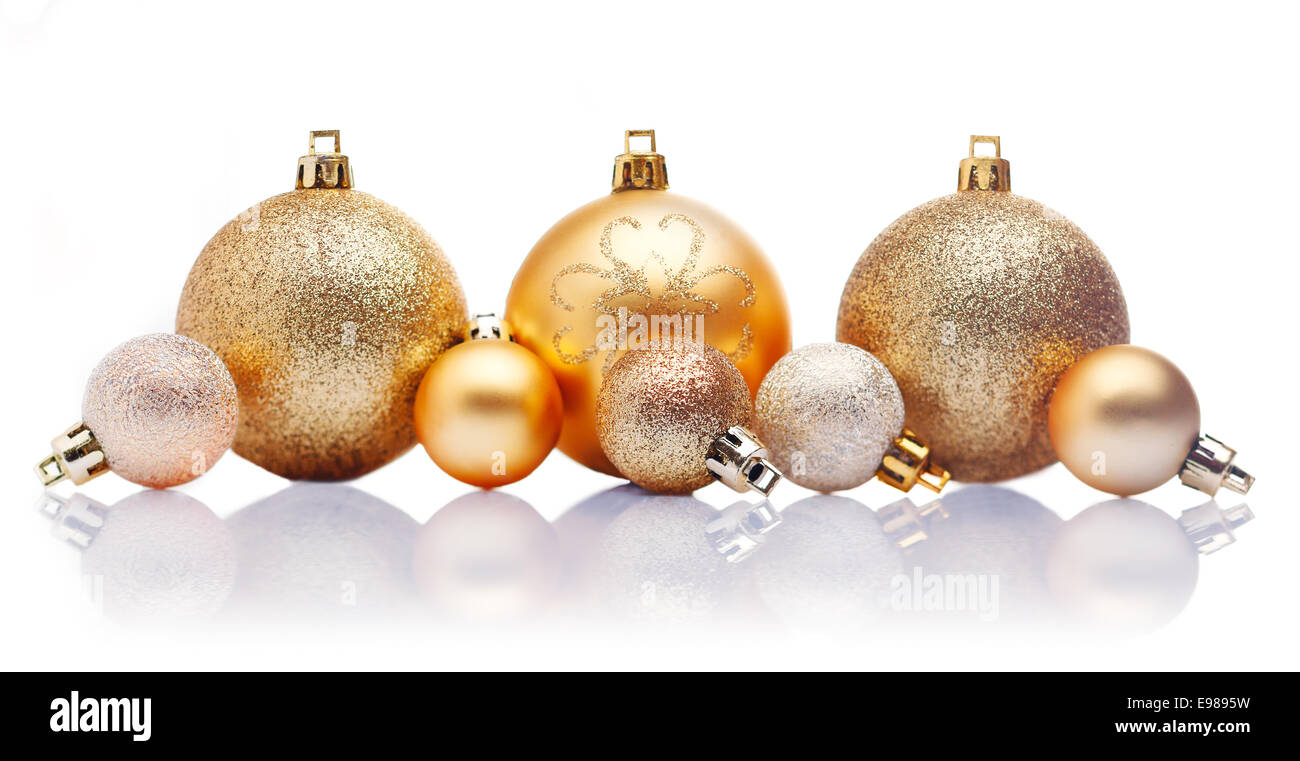 A line of large and small gold Christmas baubles with reflections against a white background Stock Photo