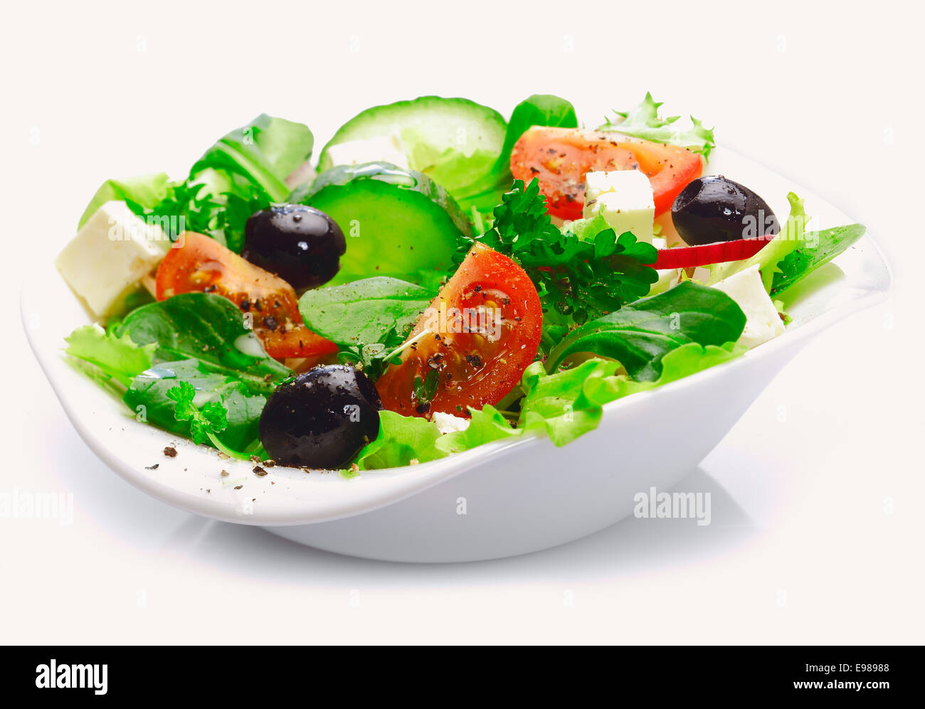 Individual side serving of delicious fresh Greek salad with feta cheese, olives, tomatoes and salad greens Stock Photo