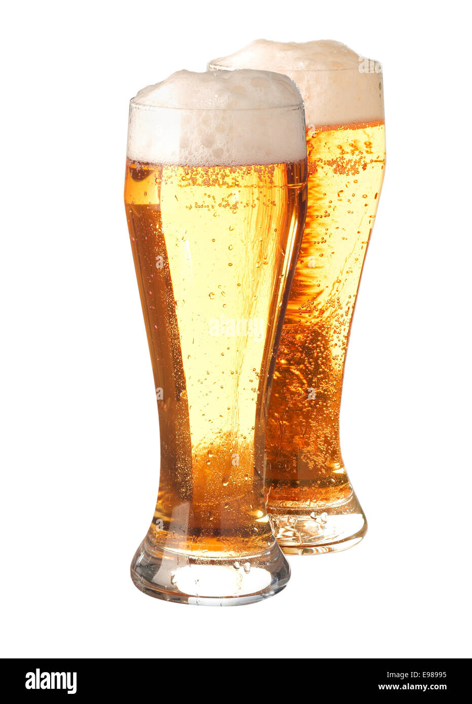 Two tall elegant pint glasses filled with pale translucent golden beer or ale with a good head of froth isolated on white Stock Photo