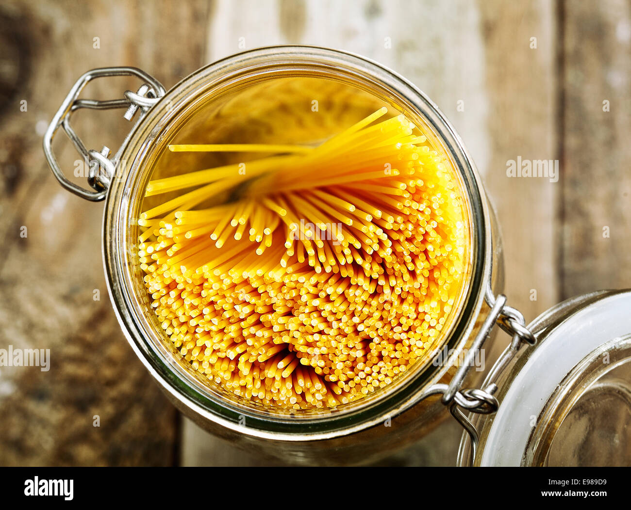 Overhead view of an open kitchen container full of spaghetti used for preparing Italian pasta dishes standing on a wooden background Stock Photo