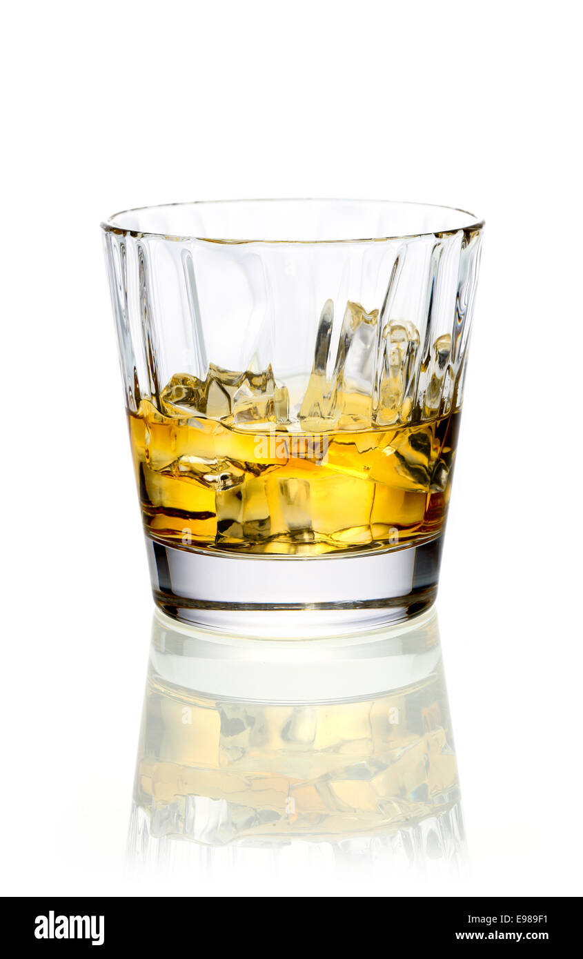 Glass of golden whiskey or brandy served on ice on a reflective white