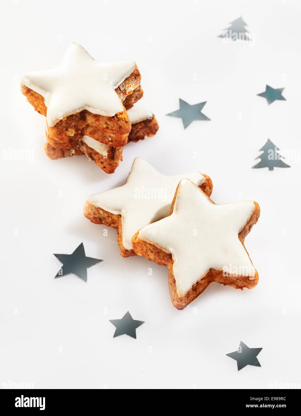 Delicious fresh crunchy Christmas star cookies with decorative white icing and scattered silver stars on a white background Stock Photo