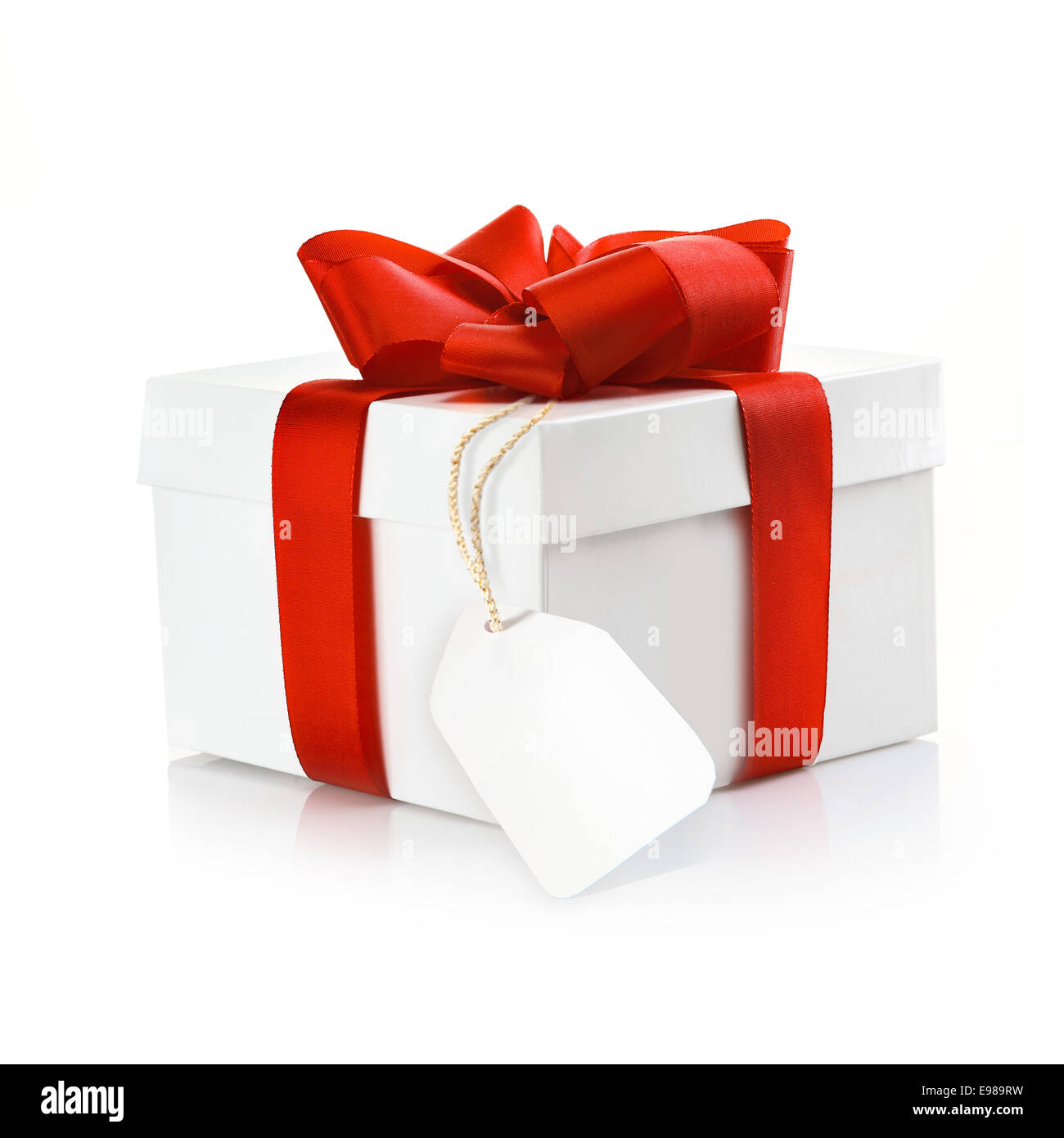 Christmas surprise gift with blank tag and a decorative red ribbon and bow on a white studio background Stock Photo
