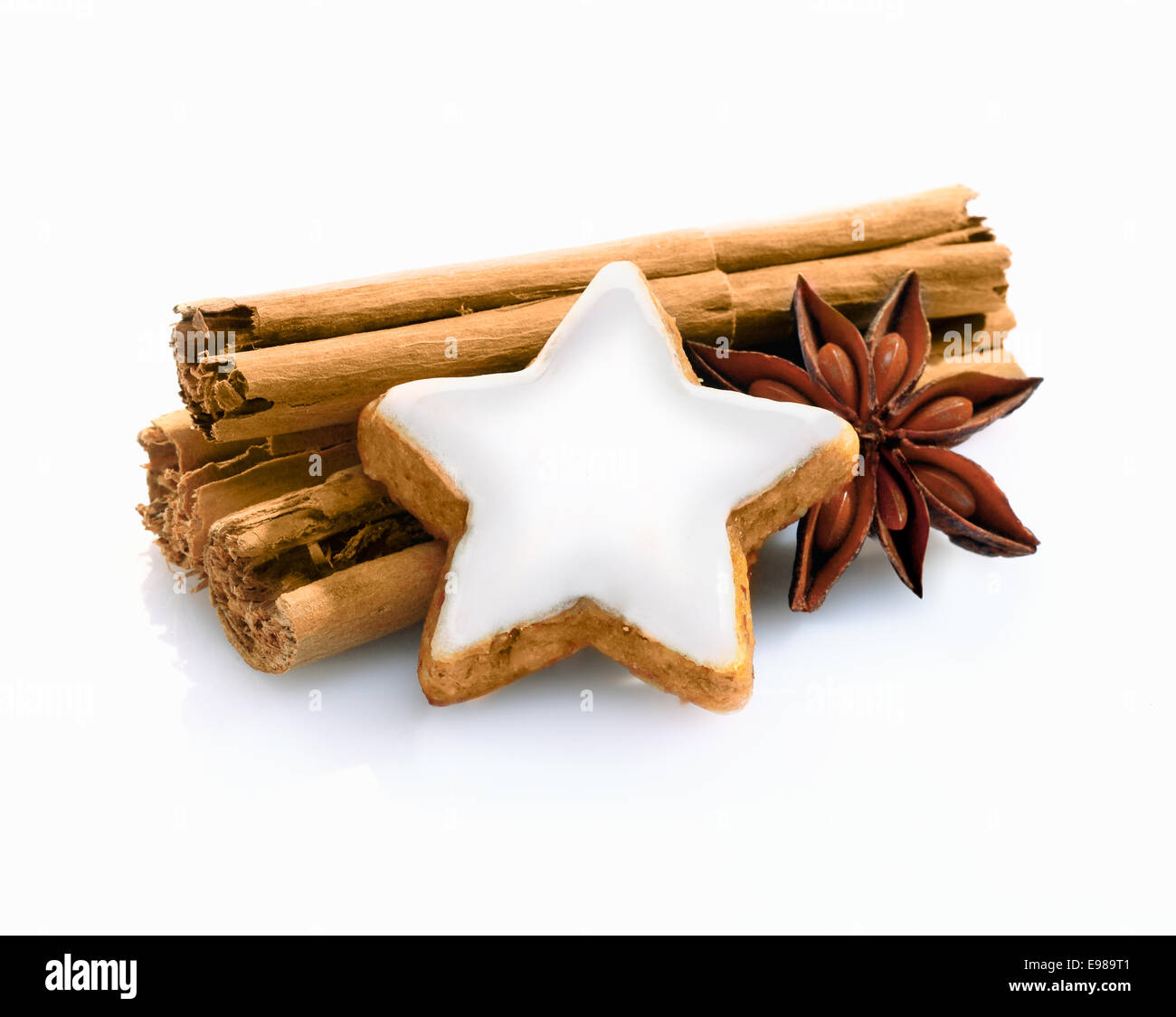Christmas spice still life with cinnamon stiicks and star anise and a decorative star shaped iced biscuit on a white background Stock Photo