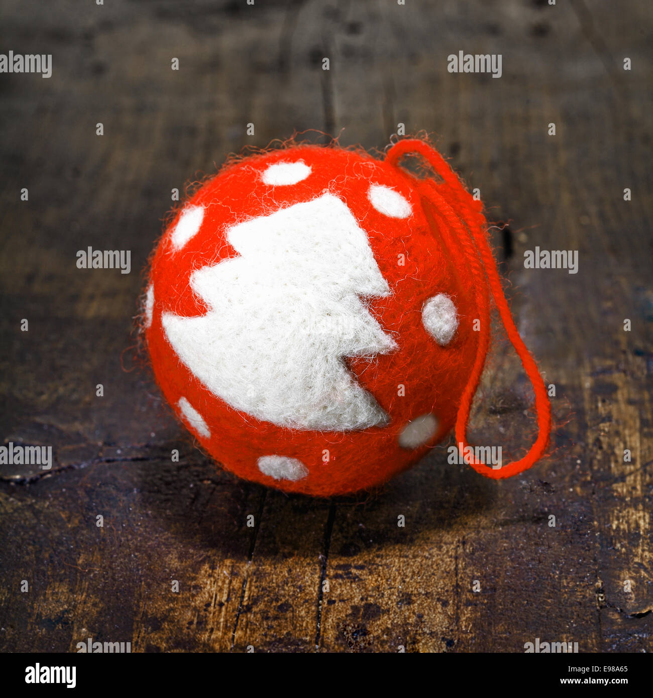 Red vintage simple handcrafted Christmas bauble with a furry texture decorated with a traditional Christmas tree on an aged wooden table Stock Photo