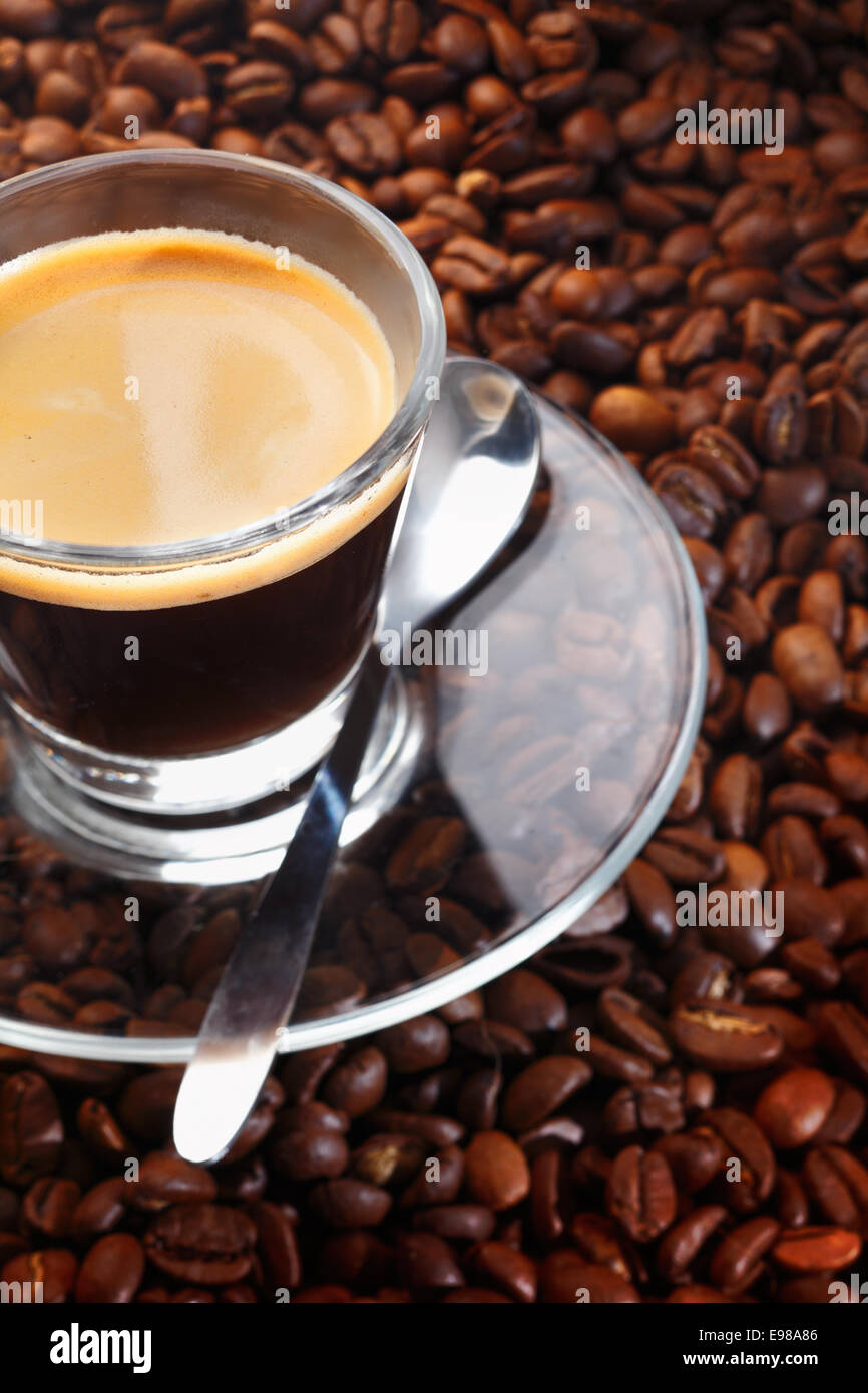 A cup of black coffee in a clear glass cup, with matching saucer and