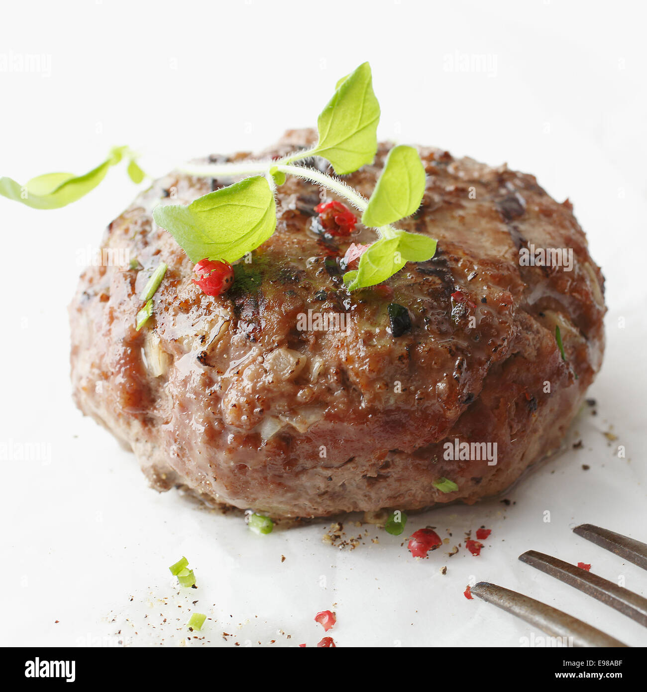 Closeup of a tasty seasoned meatball made from ground or minced beef garnished with herbs served on a white plate Stock Photo