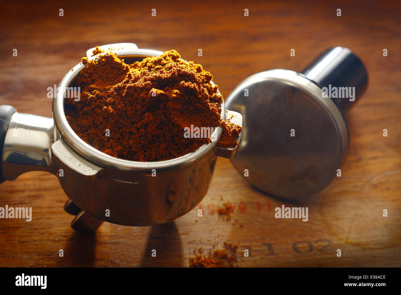 Freshly ground coffee overflowing over the rim of a metal filter onto a