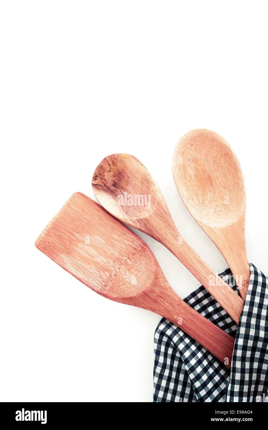 Three different types of wooden kitchen utensils in a checkered kitchen towel , on white background Stock Photo