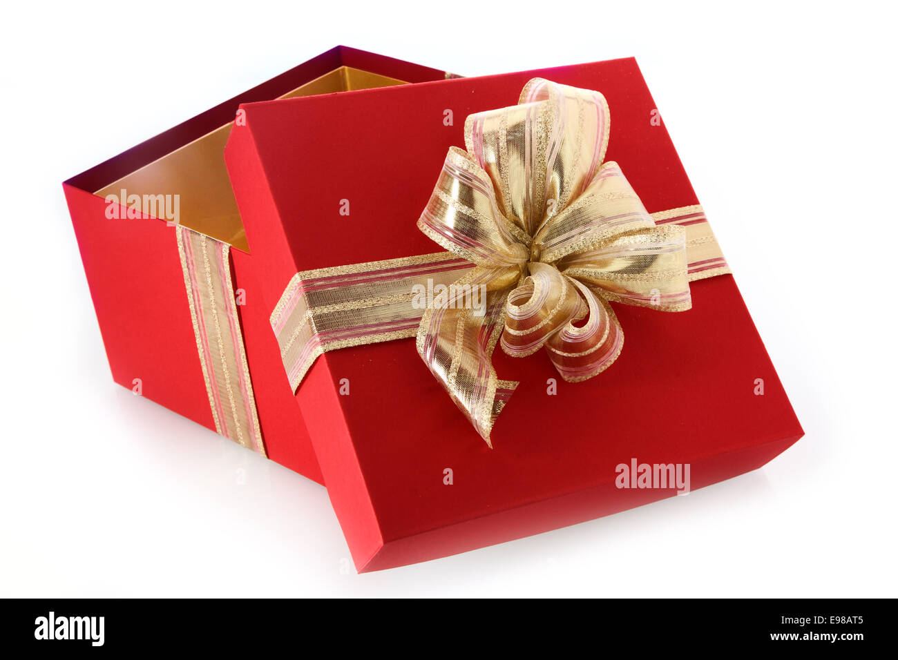 Open gift box with tilted lid and decorative gold ribbon and bow for celebrating Christmas, Valentines, birthday or an anniversary, close up view on a white background Stock Photo