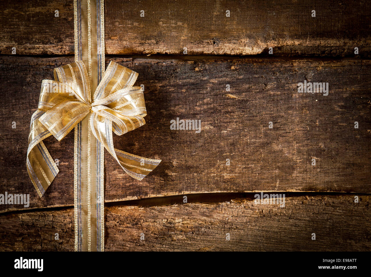 Festive ornamental gold ribbon and bow on a grunge rustic wood ...