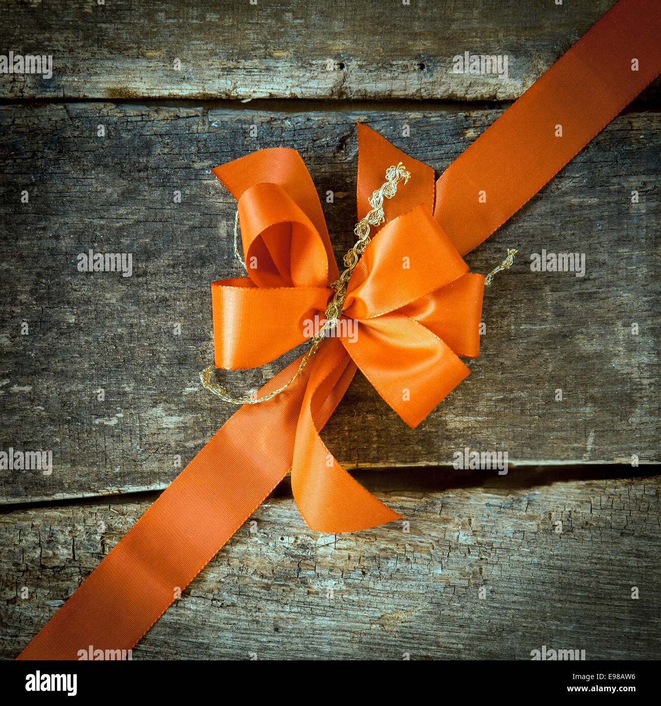 Ornamental diagonal orange ribbon and decorative bow on rustic dark ...