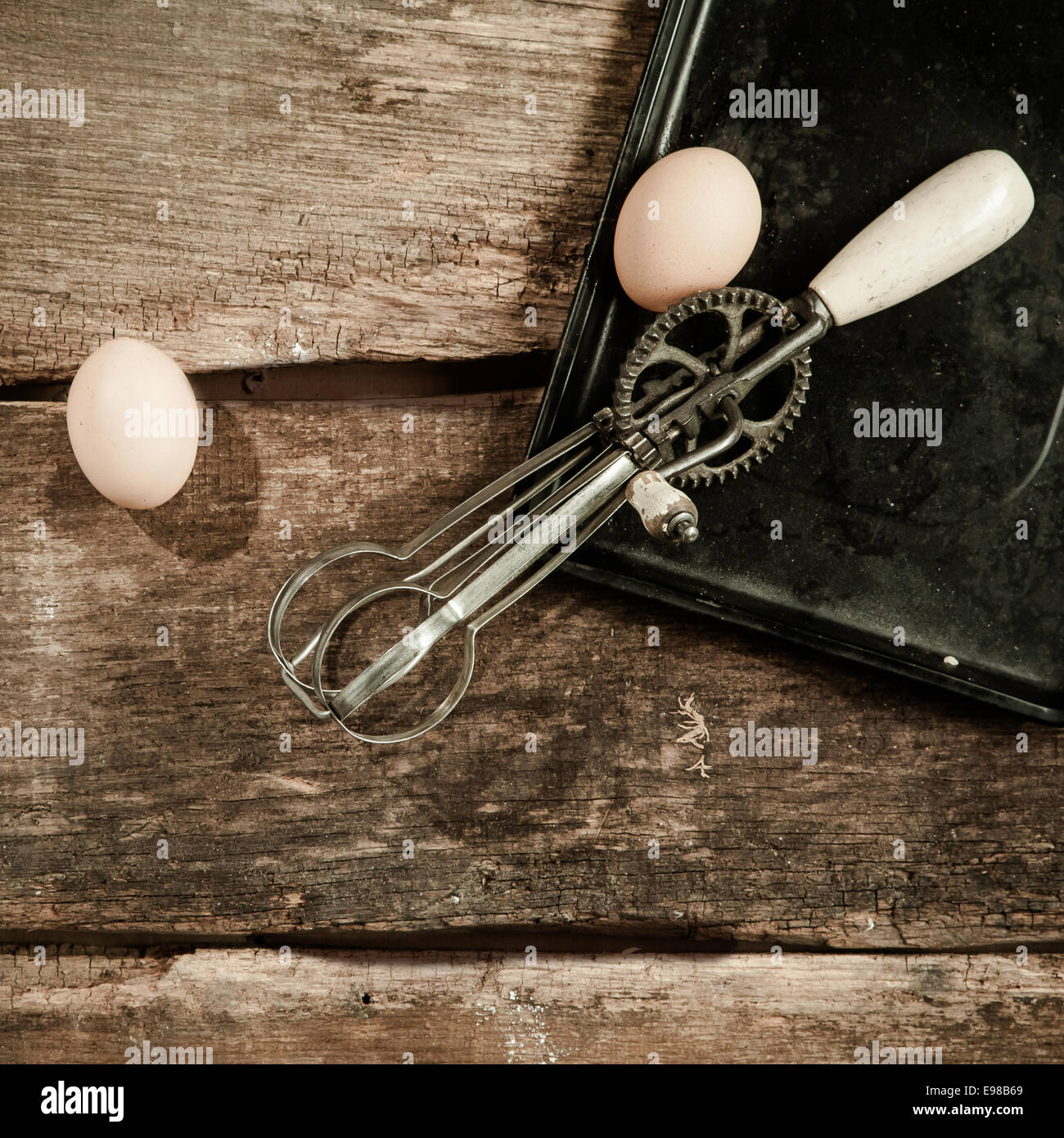 https://c8.alamy.com/comp/E98B69/high-angle-view-of-two-eggs-and-an-old-egg-beater-resting-on-a-baking-E98B69.jpg