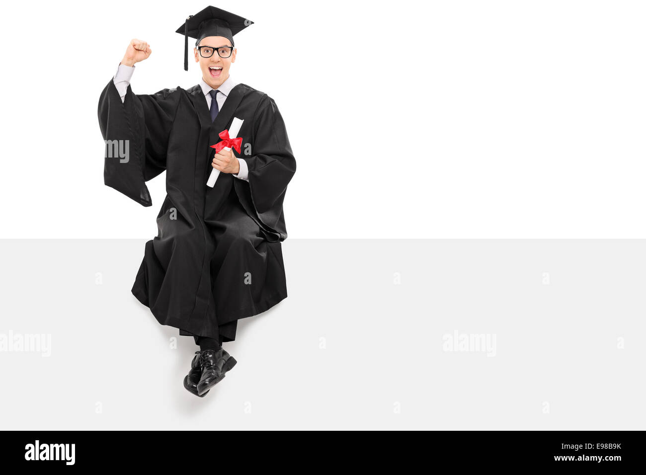 Happy college graduate holding a diploma seated on a panel isolated on ...