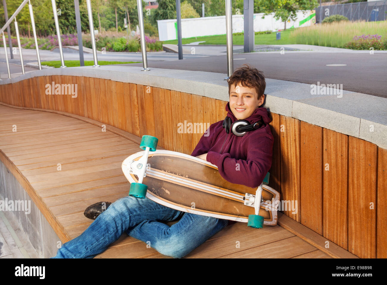 Boy with headphones relaxes and holds skateboard Stock Photo