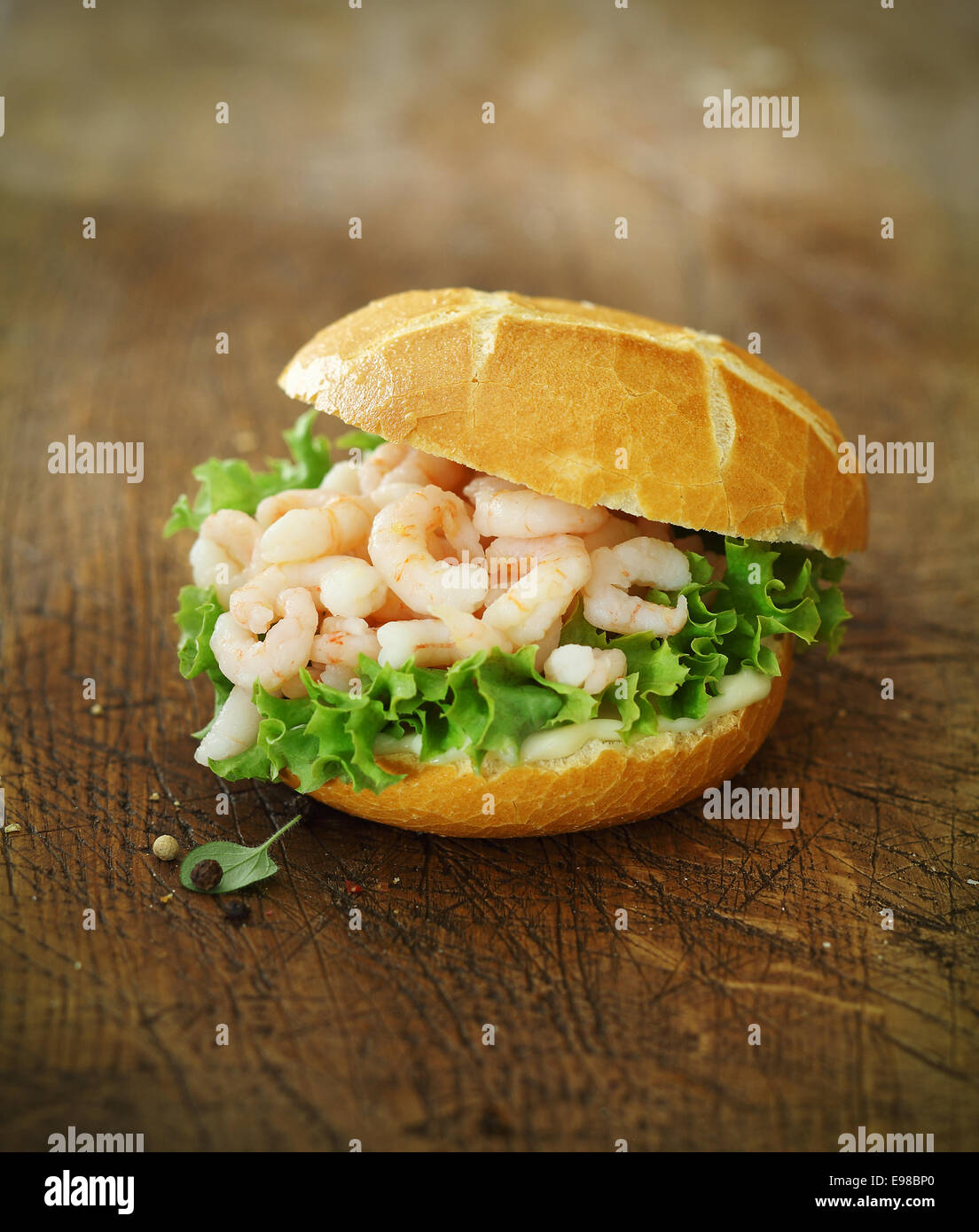 Gourmet seafood roll filled with small deveined prawns or shrimps on a bed of fresh lettuce in a crisp crusty golden roll Stock Photo