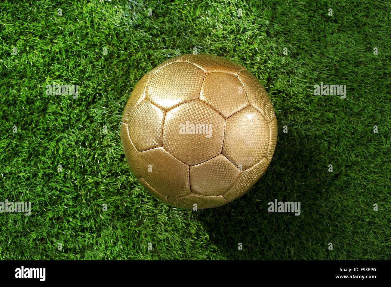 Overhead view of a gold coloured soccer ball on lush green grass with copyspace Stock Photo