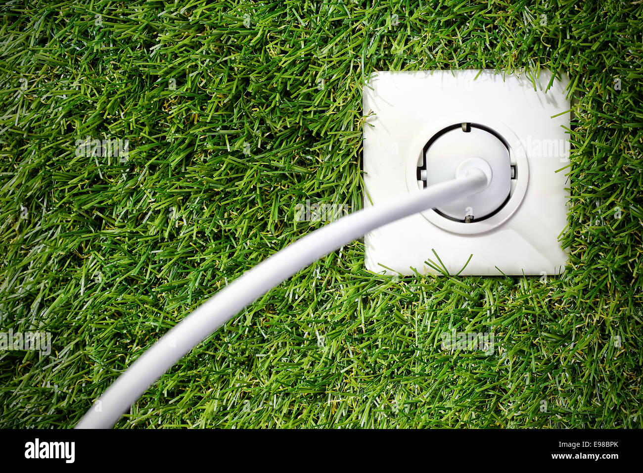 Outside white plastic electrical power point, plug and cable in a lush