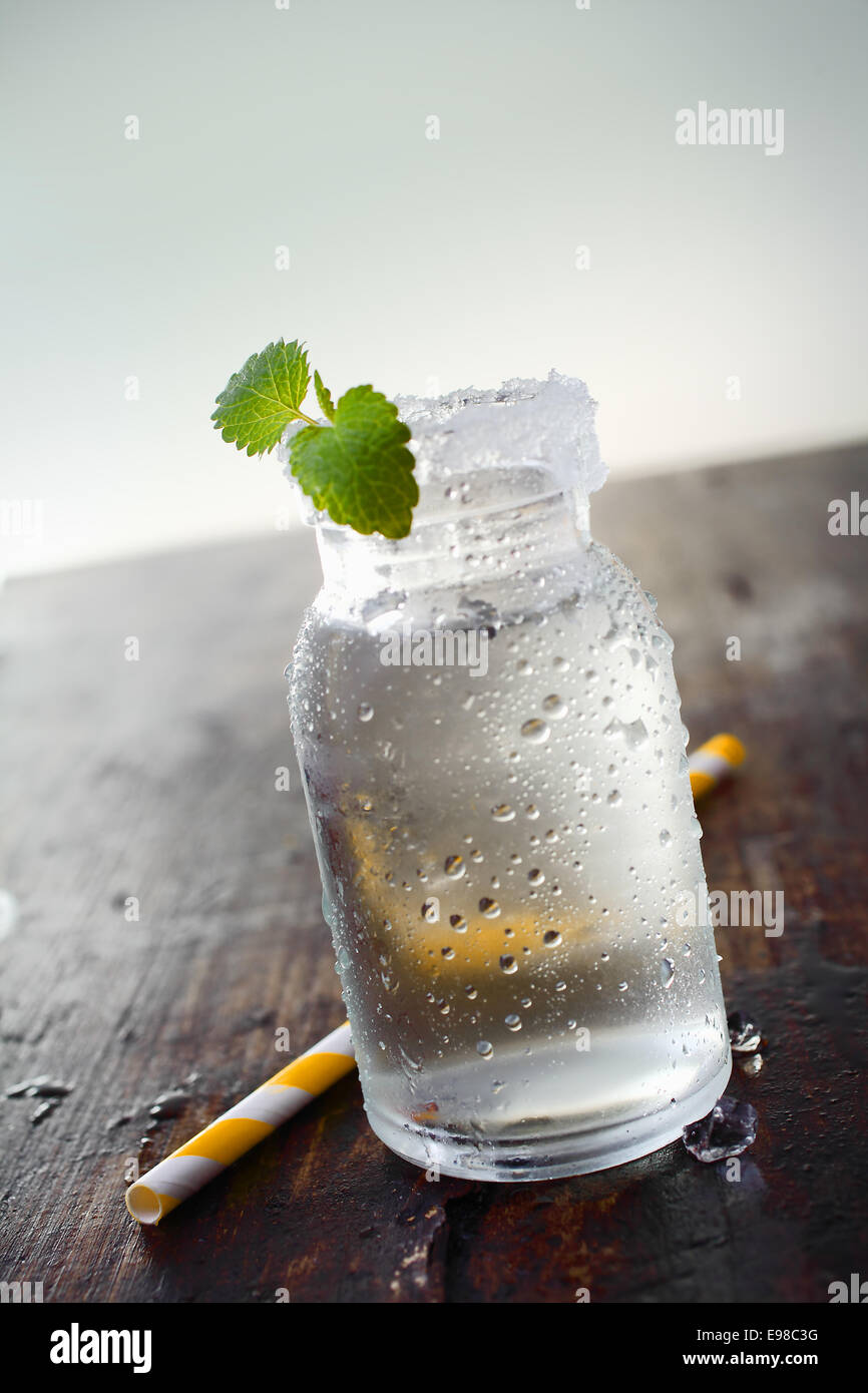 Image of a jar full of water with a small plant in it and a straw on the side. Stock Photo